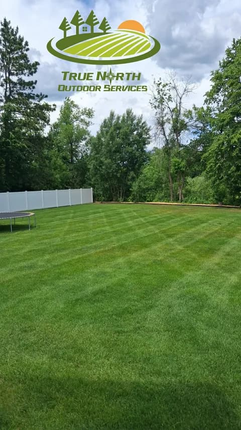 Pristine striped lawn with trampoline and privacy fence